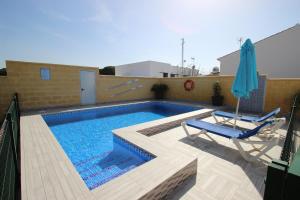 een zwembad met 2 stoelen en een parasol bij Casa Melli in Conil de la Frontera