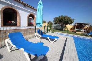 two blue chairs and an umbrella next to a swimming pool at Casa Melli in Conil de la Frontera