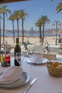 a table with a bottle of wine and a table with a view of the beach at Hotel Colón in Benidorm