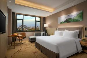 ein Hotelzimmer mit einem großen Bett und einem großen Fenster in der Unterkunft Ramada Wyndham Zhengzhou Xinzheng in Xinzheng