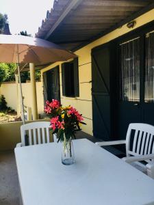 een vaas met bloemen op een tafel met twee stoelen bij Bungalows Filippi in Porto-Vecchio