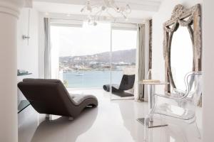 a living room with a chair and a window at Kivotos Mykonos in Ornos