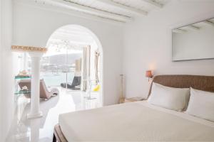 a white bedroom with a bed and an arched doorway at Kivotos Mykonos in Ornos