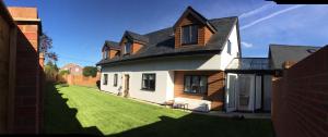 a white house with a black roof and a yard at The Acorns in Marlow