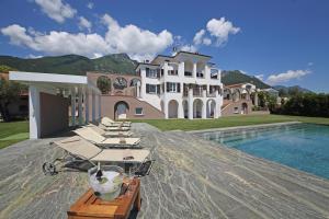 a mansion with a pool and lounge chairs on a patio at Le Selve Lake View Villas in Toscolano Maderno