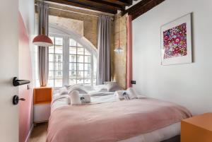 ein Schlafzimmer mit einem großen Bett und einem großen Fenster in der Unterkunft CMG Beaubourg/ Rivoli in Paris