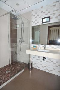 a bathroom with a shower, sink, and mirror at Hotel Ciudad de Plasencia in Plasencia