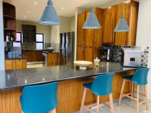 a kitchen with blue chairs at a counter at Welgemeendt Accommodation in Lichtenburg