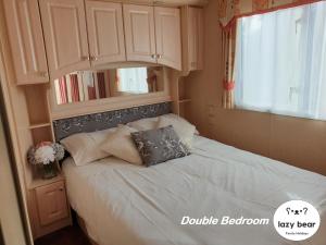 Schlafzimmer mit einem Bett mit weißer Bettwäsche und Kissen in der Unterkunft Lazy Bear, 25 Arne View in Poole