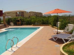 a swimming pool with an umbrella and a chair at Villa Mar - now with HEATED POOL! in Isla Canela