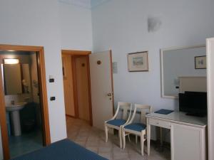 um quarto com uma secretária, 2 cadeiras e uma televisão em Hotel Miramare em Otranto