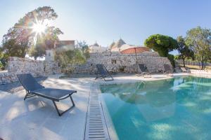 a swimming pool with a chair and an umbrella at i Trulli di Figazzano in Locorotondo
