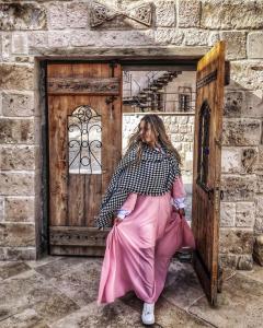 Eine Frau in einem rosa Kleid, die vor einer Tür sitzt. in der Unterkunft Mosaic Cave Hotel in Goreme