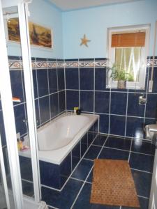 a blue tiled bathroom with a tub and a window at Casa Ramke in Eitorf