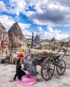 two girls sitting on the ground next to a horse drawn carriage at Mosaic Cave Hotel in Goreme