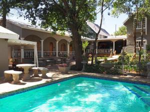 a swimming pool in front of a house at Hobbit Boutique Hotel in Bloemfontein