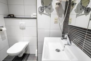 a white bathroom with a sink and a toilet at Van Der Valk Hotel Rotterdam Nieuwerkerk in Nieuwerkerk aan den IJssel