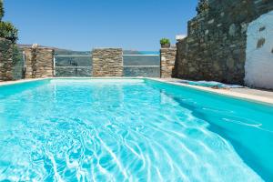 uma piscina com água azul e uma parede de pedra em Astra Residential Apts em Korthi