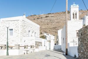biały budynek z wieżą zegarową na wzgórzu w obiekcie Astra Residential Apts w mieście Korthi