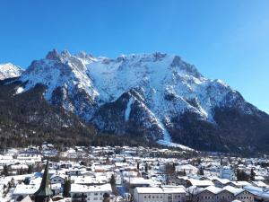 eine Stadt mit einem schneebedeckten Berg im Hintergrund in der Unterkunft Alpenappartements Schwalbennestl in Mittenwald