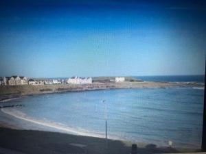 vistas a una playa con edificios y al océano en Beach Front Apt Portballintrae , Bushmills close to Royal Portrush Golf Club, en Portballintrae