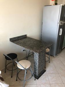 eine Küche mit einer Theke mit Hockern und einem Kühlschrank in der Unterkunft Apartamento pé na areia in Itanhaém + 28 Fotos