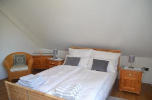 een slaapkamer met een bed met witte lakens en een stoel bij Ferienwohnung Platzek in Schneverdingen