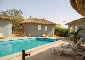 a swimming pool with two chairs and a house at Melia Hotel in Saly Portudal