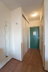 an empty hallway with a green door and wooden floors at Hotel Faber in Zandvoort