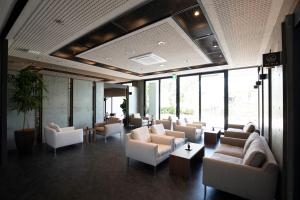 a lobby with white chairs and tables and windows at Miyajima Hanare no Yado IBUKU in Miyajima