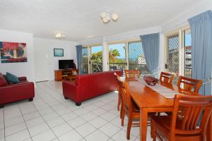 a living room with a table and a red couch at Kings Way Apartments in Caloundra