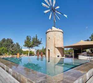 a windmill next to a swimming pool with a wind at Hotel Rural Xereca in Puig D’en Valls