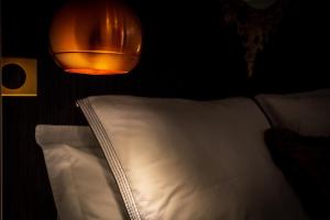 uma luz sobre uma cama com uma almofada branca em L'Appartement des Roches em Metz