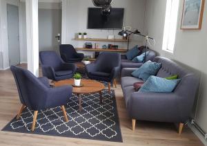 een woonkamer met een bank, stoelen en een tafel bij Hvammstangi Hostel in Hvammstangi