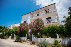 a white house with pink flowers in front of it at Apartments Petrčane Welcome in Petrcane