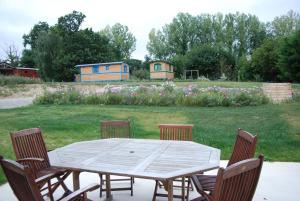 una mesa de madera con sillas y un campo con casas en La Ferme du Chauchix, en Lamballe