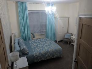 a bedroom with a bed with blue curtains and a chandelier at Lion House Bed & Breakfast with Restaurant in Combe Martin
