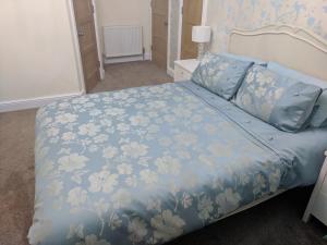 a bedroom with a bed with a blue floral bedspread at Lion House Bed & Breakfast with Restaurant in Combe Martin