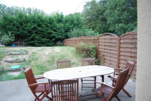 d'une terrasse avec une table, des chaises et une clôture. dans l'établissement La Ferme du Chauchix, à Lamballe