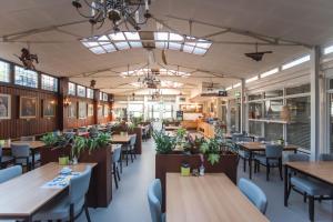 a dining room with tables and chairs and windows at Hotel Faber in Zandvoort