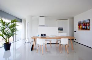 a white kitchen with a wooden table and white chairs at Urban Residences Rotterdam in Rotterdam