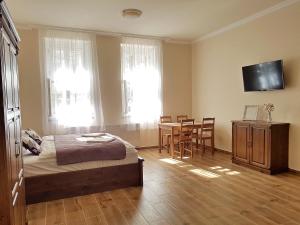 a bedroom with a bed and a table and a television at Toscana Apartman in Gyula