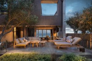 un patio con 2 sofás, una mesa y sillas en The Olive Tree Villa en Yzerfontein