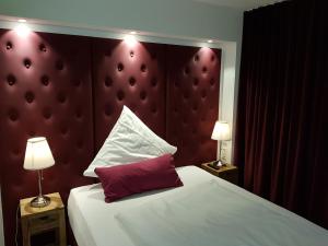 a bedroom with a bed with a red headboard and two lamps at Gasthof Krone in Adelberg