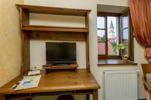 a living room with a tv and a desk with a television at Burgschänke & Herberge Goldener Löwe in Bad Düben