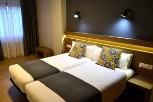 a hotel room with a large bed with pillows at Hotel Alda Estación Pontevedra in Pontevedra