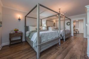 Harbor House Inn في Sackets Harbor: غرفة نوم بسرير مظلة وأرضية خشبية