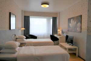 a hotel room with two beds and a television at Linnanpiha Bed & Breakfast in Rauma