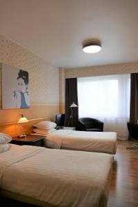Habitación de hotel con 2 camas y escritorio en Linnanpiha Bed & Breakfast en Rauma