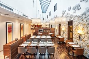 a restaurant with tables and chairs and a stone wall at H4 Hotel Münster in Münster